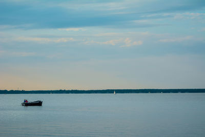 Boat sailing in sea against sky during sunset