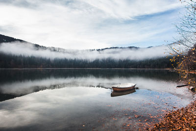 Boat floating on lake against sky