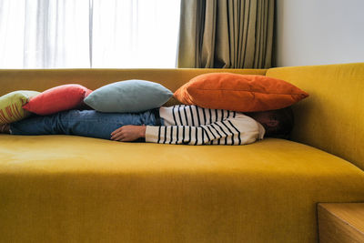 Low section of woman sitting on sofa at home