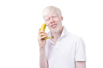Young man eating food against white background