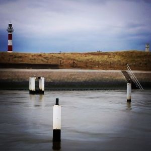 Lighthouse by lake against sky