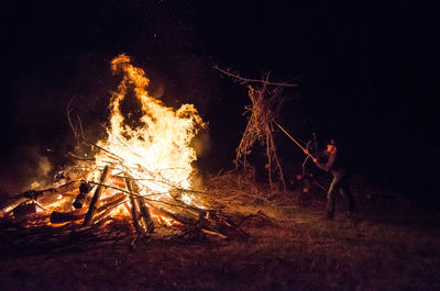 Man putting wood in fire on field