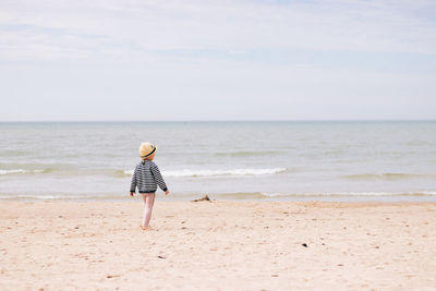 Rear view of person on beach against sky