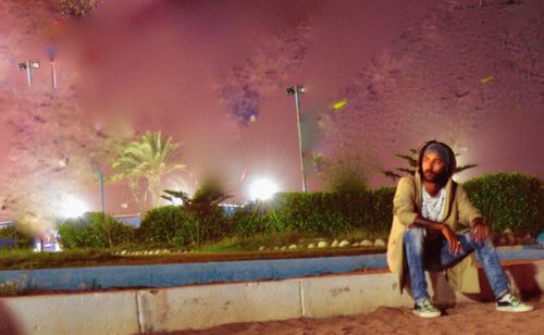 Young couple sitting on illuminated street light at night