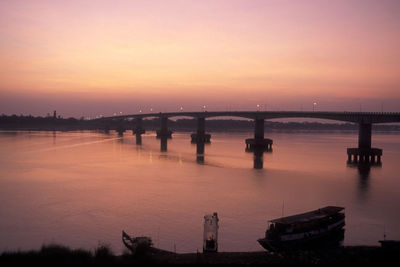 Silhouette bridge over river against romantic sky at sunset