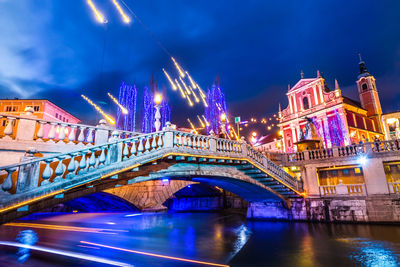 Illuminated bridge over river at night