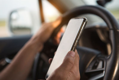 Cropped hands using mobile phone while driving car