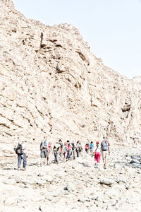 People hiking on mountain against clear sky