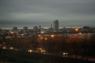 Illuminated cityscape against sky at dusk