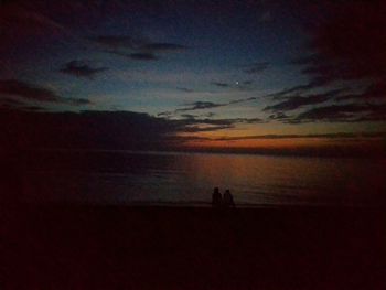 Silhouette people on beach against sky during sunset