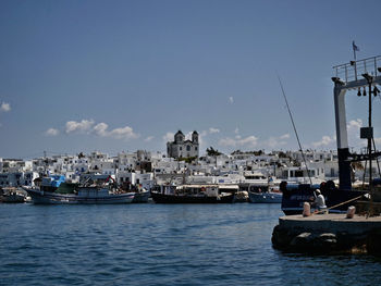 Sailboats moored on harbor by buildings in city