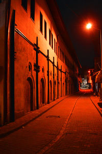 Empty road along buildings at night