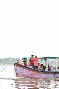 People sitting on boat against clear sky