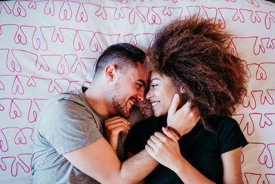 High angle view of romantic young couple lying on bed at home