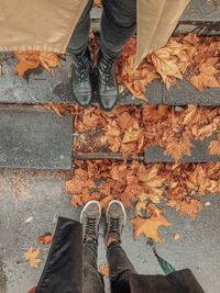 Low section of man standing on autumn leaves