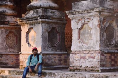 Portrait of young man sitting by architectural columns