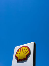 Low angle view of yellow flag against clear blue sky