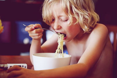 Shirtless boy having noodles