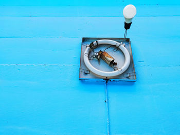 Close-up of electric lamp hanging against blue wall