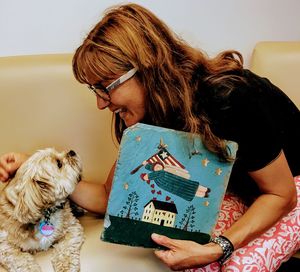 Smiling woman playing with dog at home