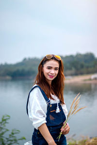 Portrait of smiling young woman standing against sky