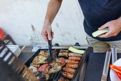 Upper view of man cooking vegetables and meat on a grill in the garden