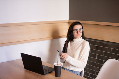 Portrait of young woman using mobile phone while sitting at home