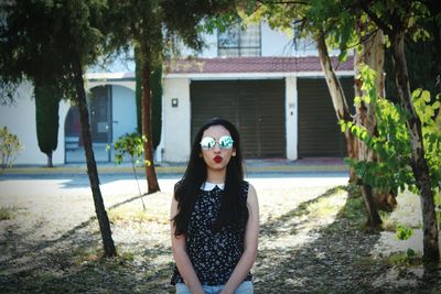 Portrait of young woman standing against house