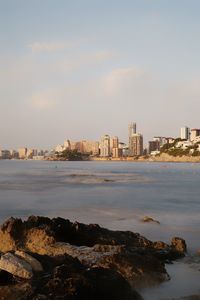 Sea by buildings against sky in city