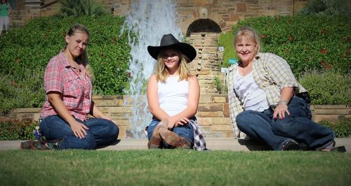 Portrait of female friends sitting against fountain at park