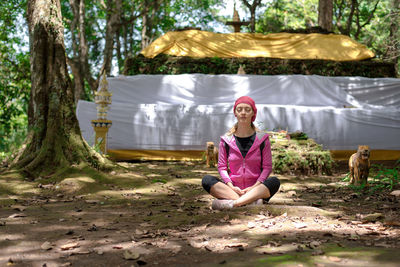 Portrait of woman sitting on land against trees