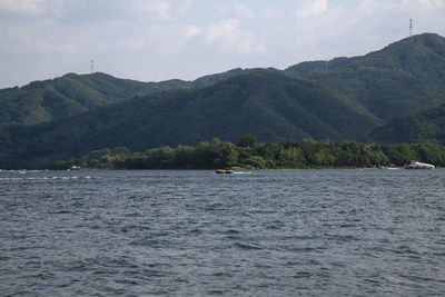 Scenic view of sea by mountains against sky