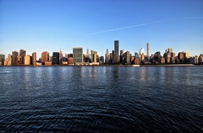 Sea and buildings in city against blue sky