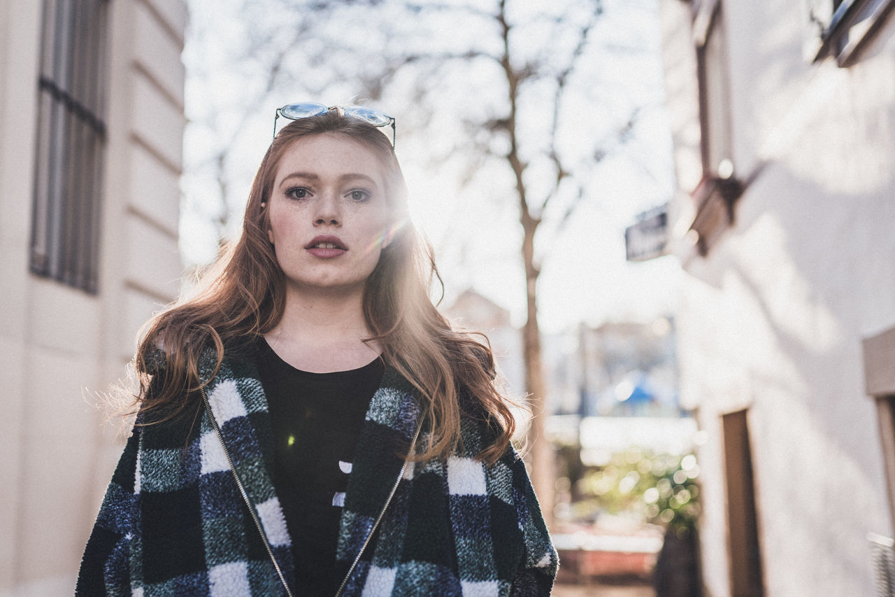 portrait, architecture, built structure, building exterior, front view, one person, young adult, young women, looking at camera, beauty, day, beautiful woman, lifestyles, focus on foreground, hairstyle, casual clothing, standing, hair, outdoors, teenager, warm clothing