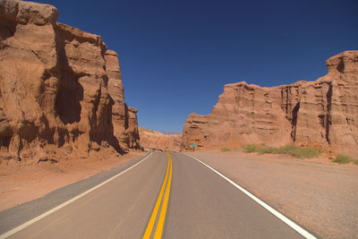 Rear view of man walking on road against clear sky