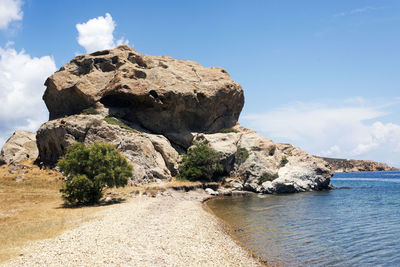 Rock formation by sea against sky