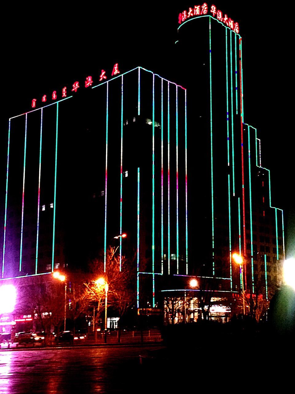 illuminated, night, building exterior, architecture, built structure, city, lighting equipment, street light, light - natural phenomenon, low angle view, modern, multi colored, outdoors, sky, long exposure, street, glowing, building, no people, reflection