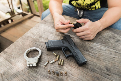 Midsection of man holding handgun at wooden table in balcony