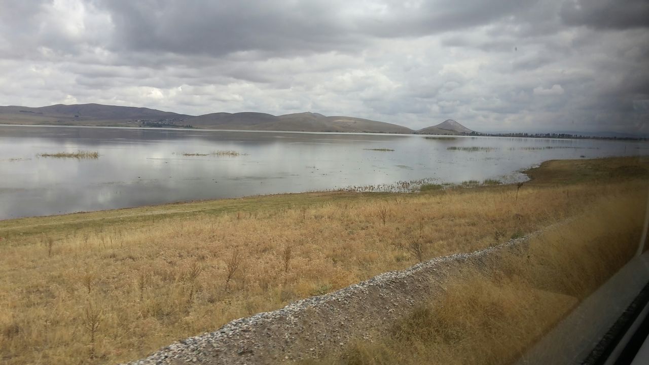 sky, water, cloud - sky, lake, cloudy, tranquil scene, tranquility, scenics, mountain, beauty in nature, cloud, nature, grass, reflection, river, weather, landscape, idyllic, day, mountain range