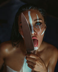 Close-up portrait of young woman holding kitchen knife