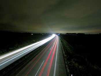 Light trails on road against sky at night