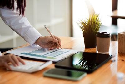 Midsection of woman working with book on table