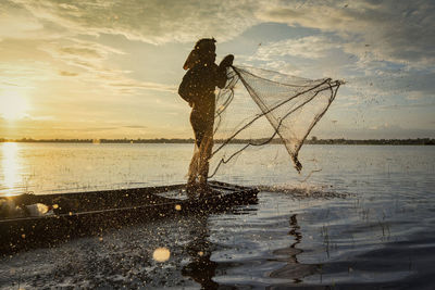 Side view of man throwing net in river