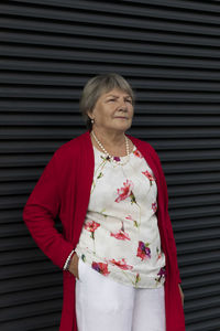 Closeup real senior old 70s pensioner, dark wall on background. portrait of kind relaxed elderly