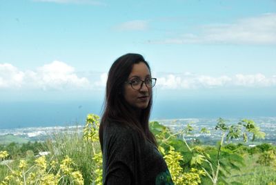 Young woman standing by sea against sky