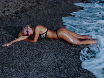 High angle view of young woman in bikini lying at beach