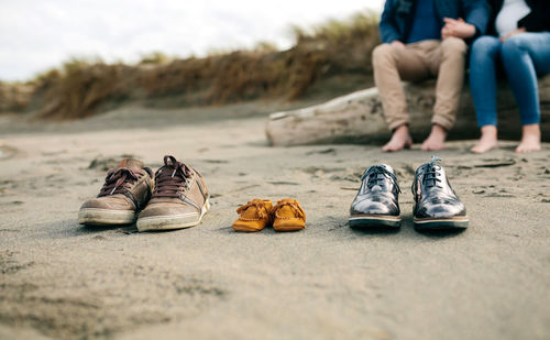 Low section of men sitting on sand
