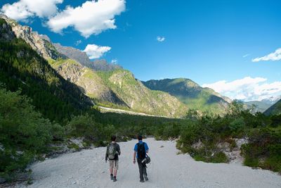 Rear view of men walking on mountain against sky