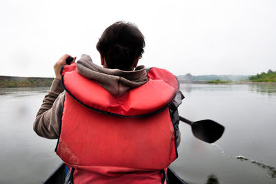 Rear view of man in boat at calm lake