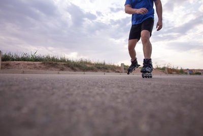 Low section of man skateboarding on road